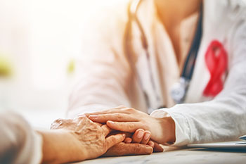 A close-up of a doctor with their hands atop a patient's hands