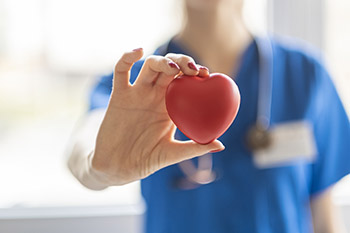 A doctor holding up an apple between their fingers