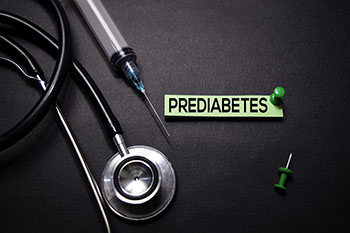A stethoscope and needle next to a slip of paper saying Prediabetes