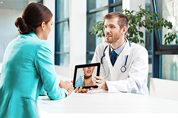A doctor showing a patient a presentation image of her face post-operation