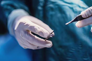 A close up of a surgeons hands holding utensils